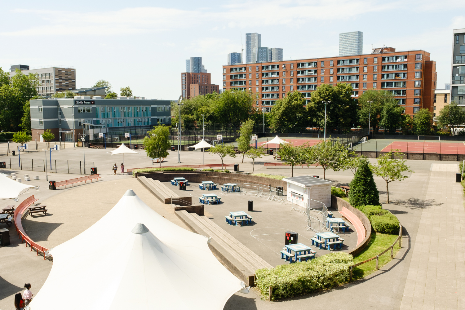 Trinity School Amphitheatre, Sixth Form and the Manchester skyline on a sunny day.